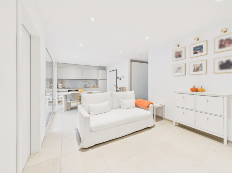 modern living room with white couch, white tiled floor, white cabinet, dining area, kitchen