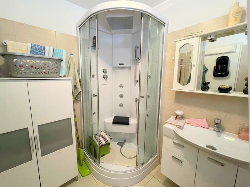 modern bathroom with white cabinets, a sink, shower cubicle, and a toilet