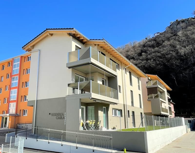 Modern apartment building with balconies, three stories, orange and white facades, fenced entrance