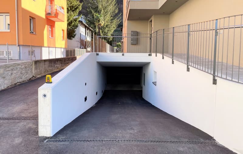 Entrance to a garage with a metal railing and yellow safety cone