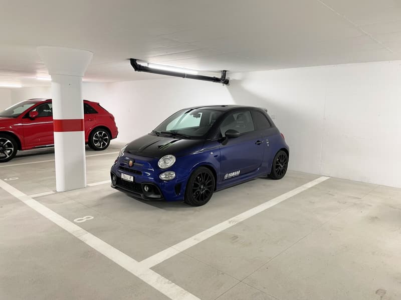 Underground parking space with white walls, pillar, 2 parked cars