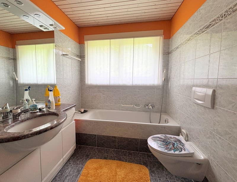Bathroom with bathtub, toilet, sink with mirror, and floor tiles