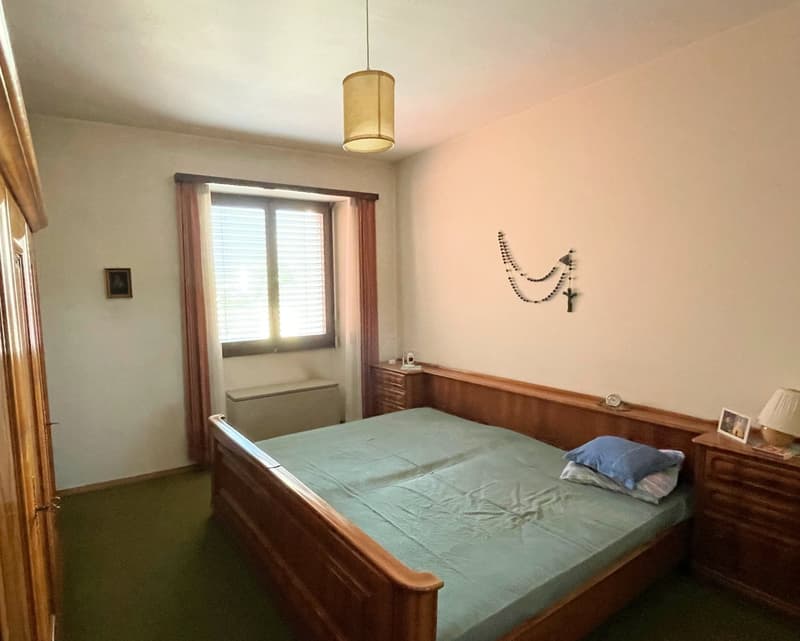 bedroom with bed, bedside tables, lamp, framed picture, wardrobe, window with curtains, heater