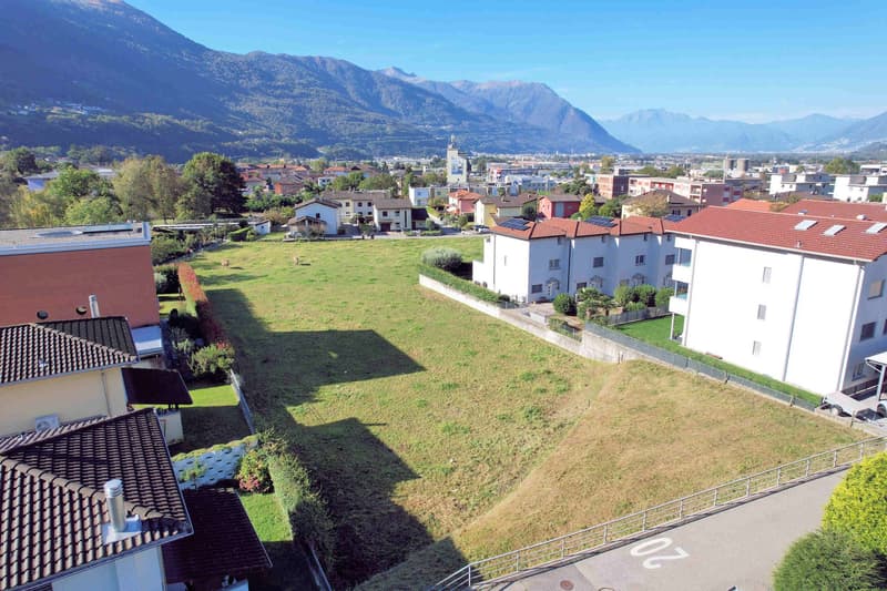 Flat terrain, grass, residential buildings, town, mountains in background