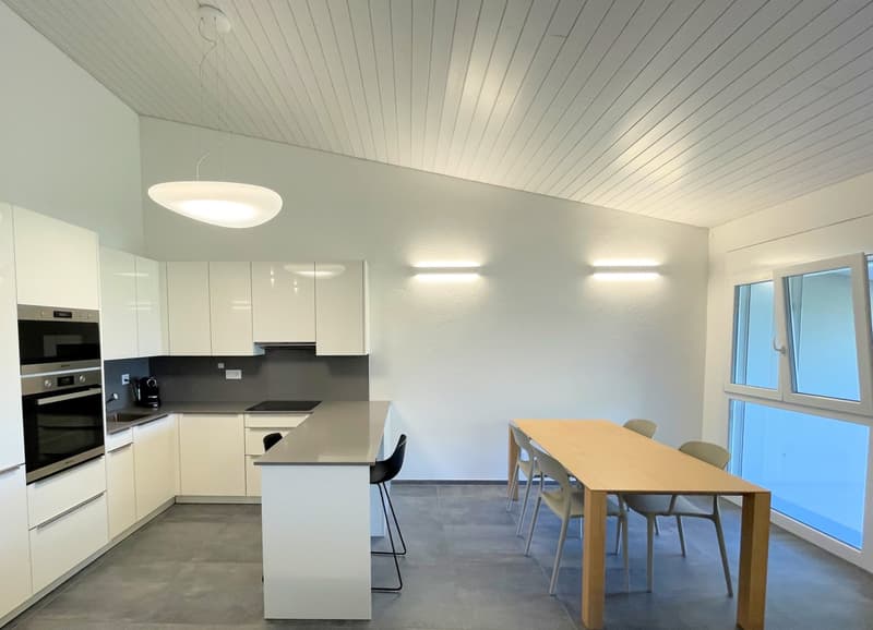 modern kitchen with white cabinets, gray countertops, built-in oven and coffee machine, dining table with chairs, large windows