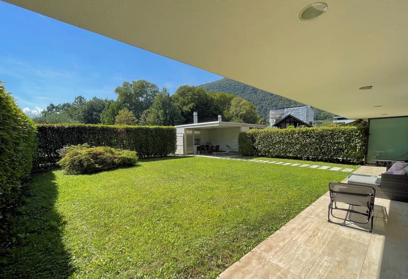 well-maintained garden, green lawn, hedges, patio with outdoor furniture, balcony with view