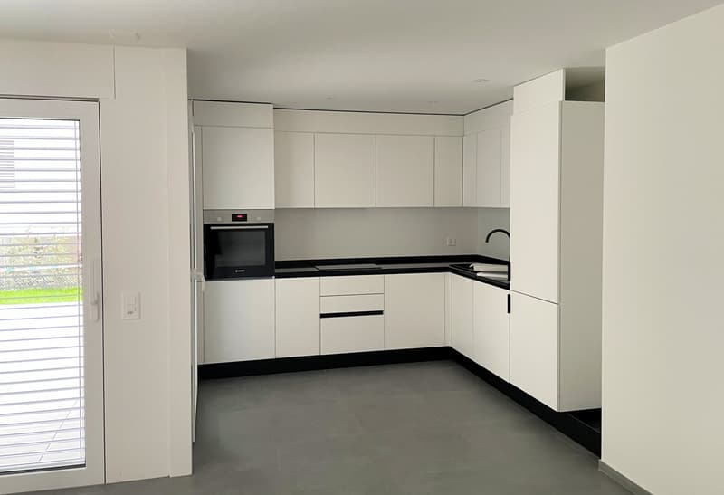 modern kitchen with white cabinets, black countertops, built-in oven, sink with faucet, dishwasher, washing machine