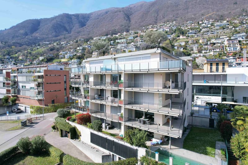 Modern apartment building with multiple balconies, swimming pool, and a view of the mountains
