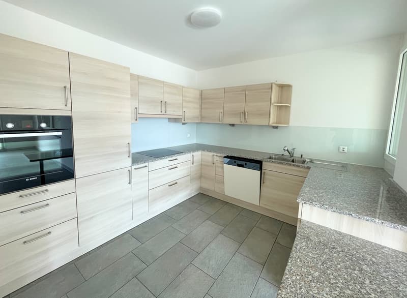 modern kitchen with wooden cabinets, granite countertops, built-in oven and dishwasher, gas stove, sink with faucet, and a window