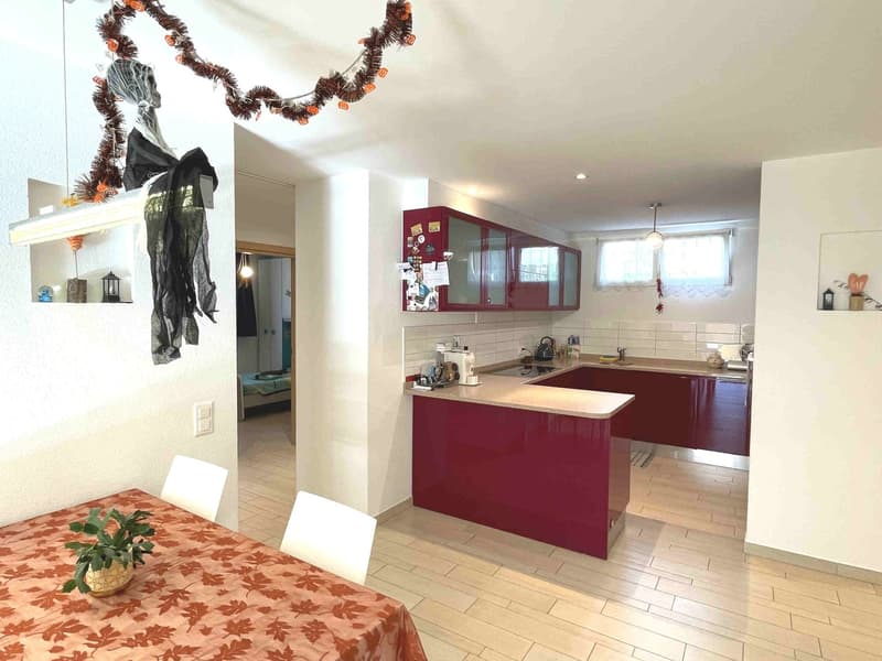 modern kitchen with red cabinets, white tiled backsplash, island with sink, dishwasher, and washing machine