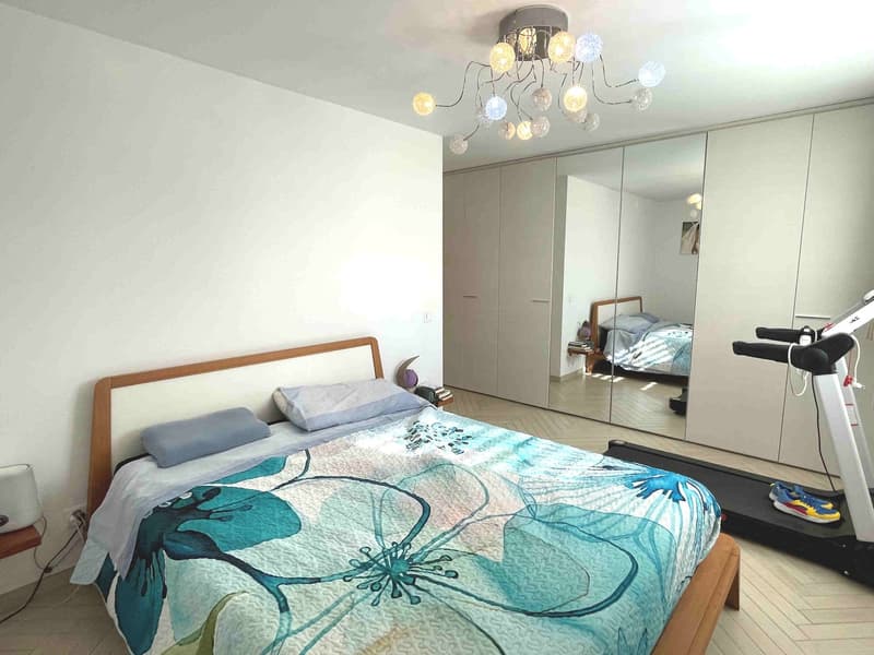 Bedroom with bed, treadmill, chandelier, closet, mirror, nightstand, and lamp