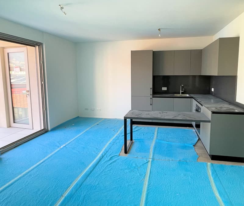 empty kitchen with blue tarp on the floor, sliding door to balcony, gray cabinets, granite countertop, sink, faucet