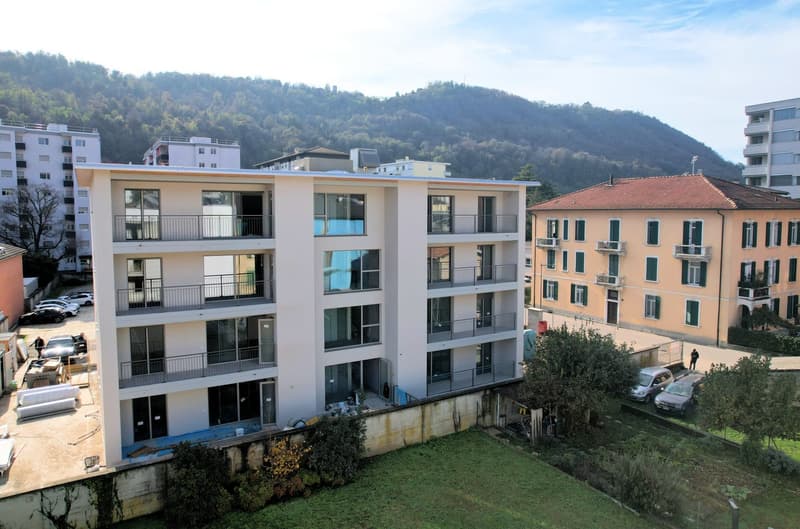 Modern apartment building with multiple balconies, located in a scenic area with a mountain view