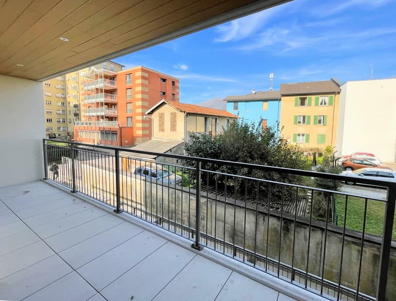 Balcony with metal railings, tiled floor, view of the street and buildings