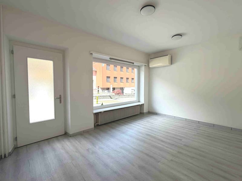 empty room, white walls, wooden floor, white door, large window, radiator, air conditioner