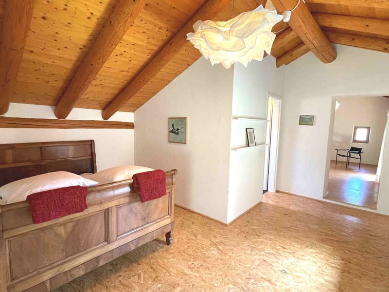 wooden bed, wooden ceiling, wooden floor, white walls, two pillows, red towels, picture frames, lamp, mirror