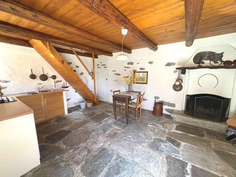 kitchen with stone floor, wooden ceiling, fireplace, dining table, wooden stairs