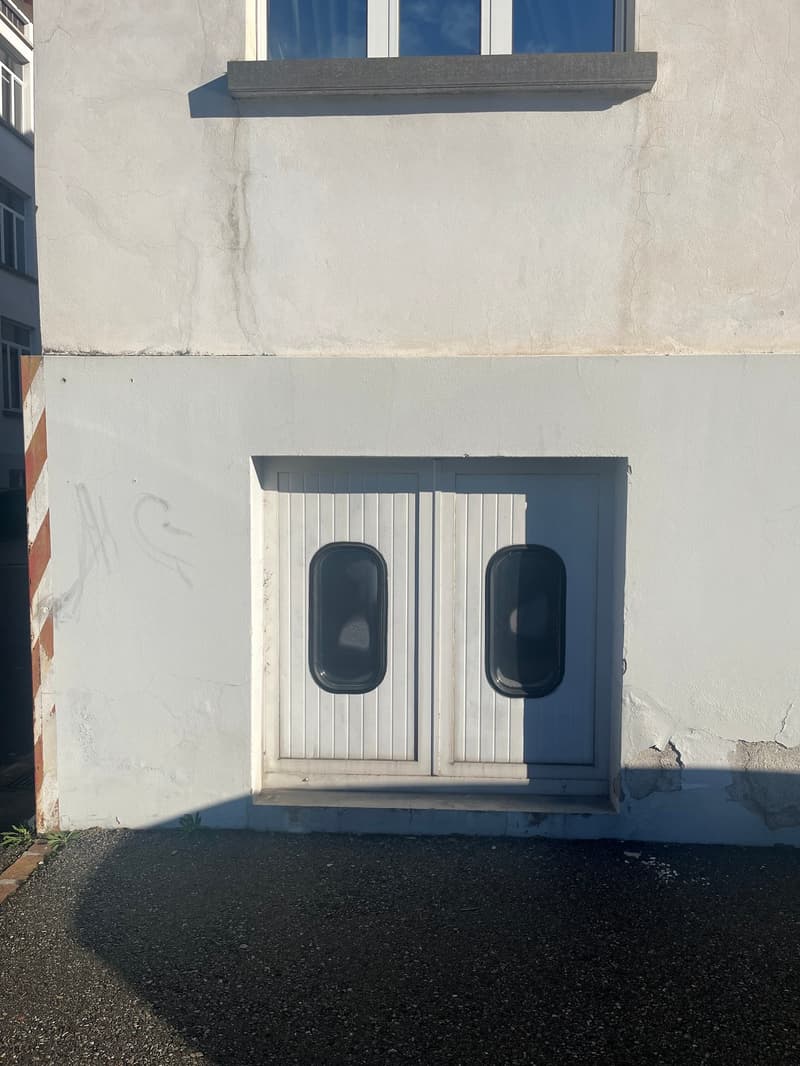 White exterior building with a garage entrance on the lower floor, located on the street side.