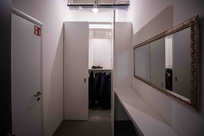 A narrow hallway with a mirror, coat rack, and closet on the right side, and a door on the left.