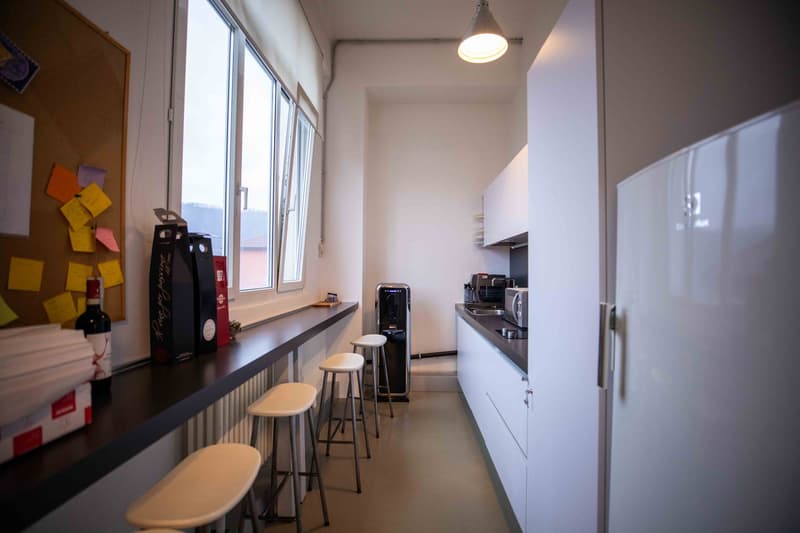 kitchen area with window view, counter top, stools, white cabinets, appliances