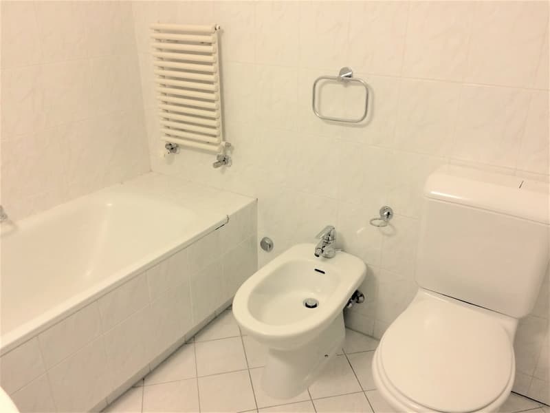 The image shows a bathroom with a white toilet, a white sink, and a white towel rack. The bathroom appears to have tile flooring and walls.