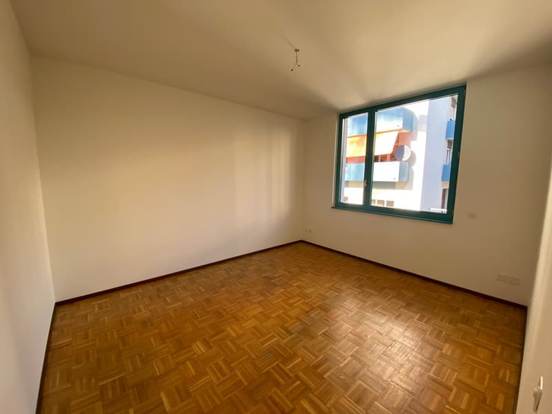 empty room, wooden floor, white walls, window with green frame, power outlets on wall