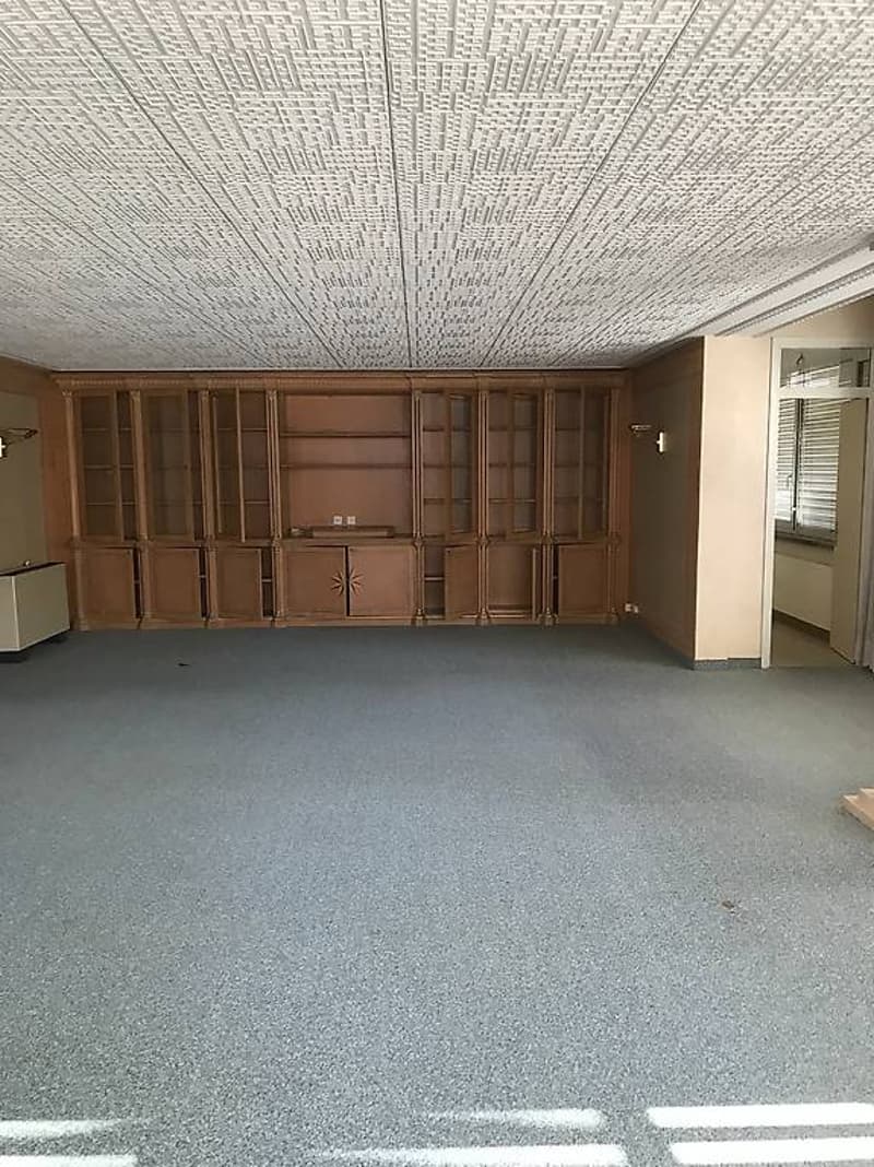 Empty room with carpet flooring, large wooden cabinets, two lamps on the walls, white ceiling.