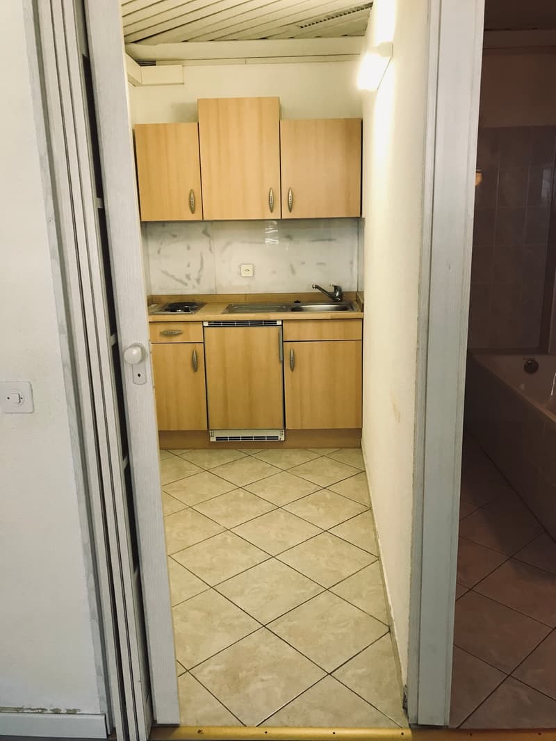 small kitchen with gas stove, sink, cabinets, tiled floor