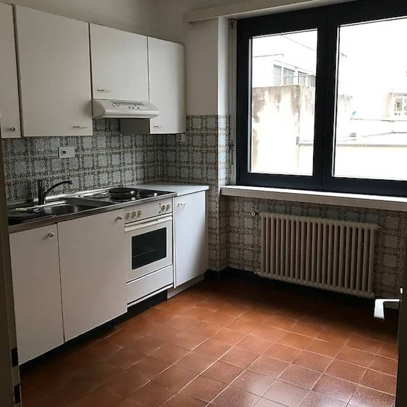 modern kitchen, white cabinets, tile flooring, gas stove, oven, sink, large window, radiator