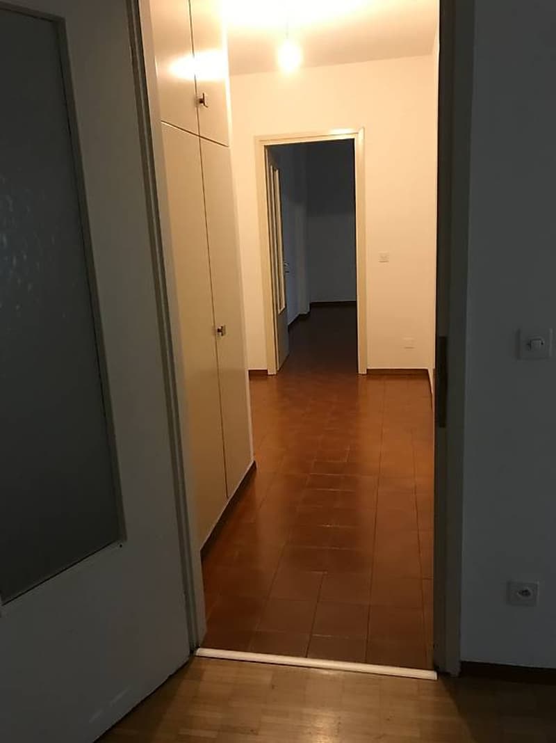 Empty room, wooden floor, white walls, open doors, light on