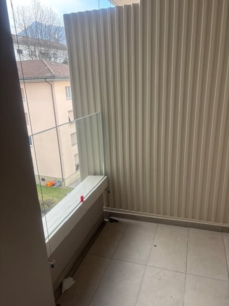 Empty room with glass wall, tile floor, and a balcony with a window sill
