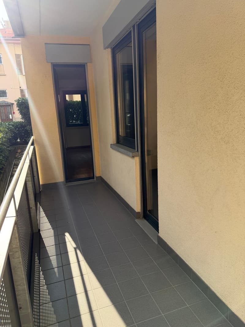 a balcony with tiled floor, railings, and glass doors leading to a room