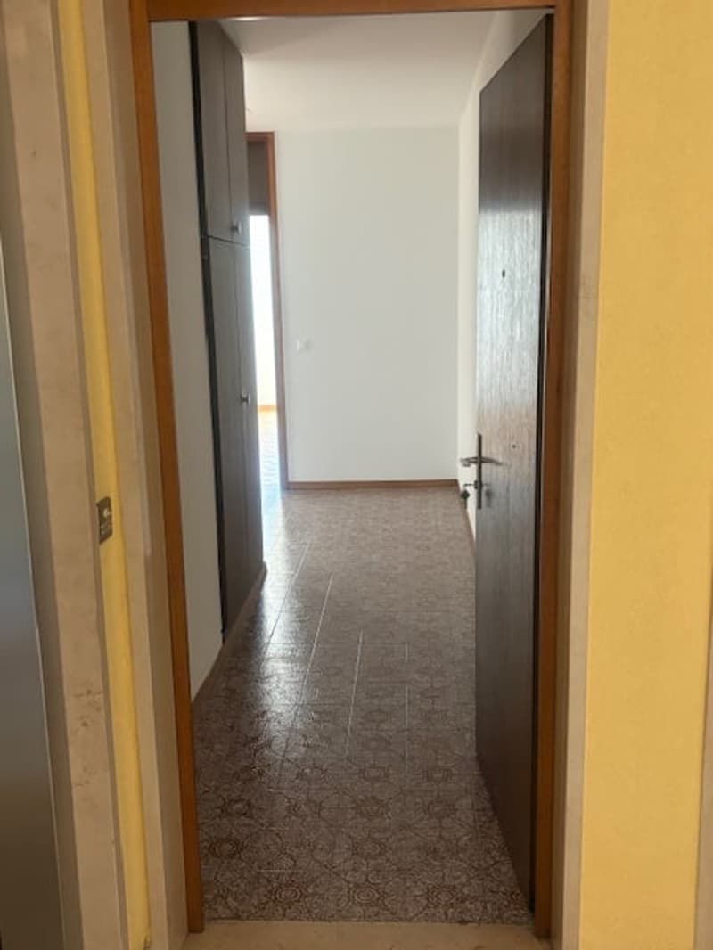 Empty hallway with tiled floor, yellow walls, and two doors.
