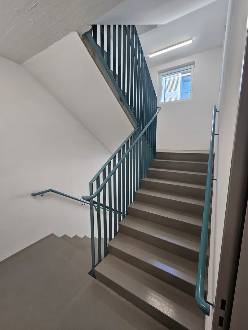 concrete raised ground floor, turquoise railings, light ceiling, window