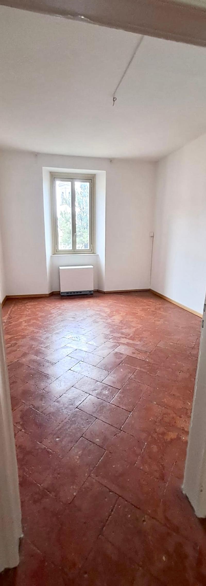 empty room with terracotta floor, white walls, window with white frames