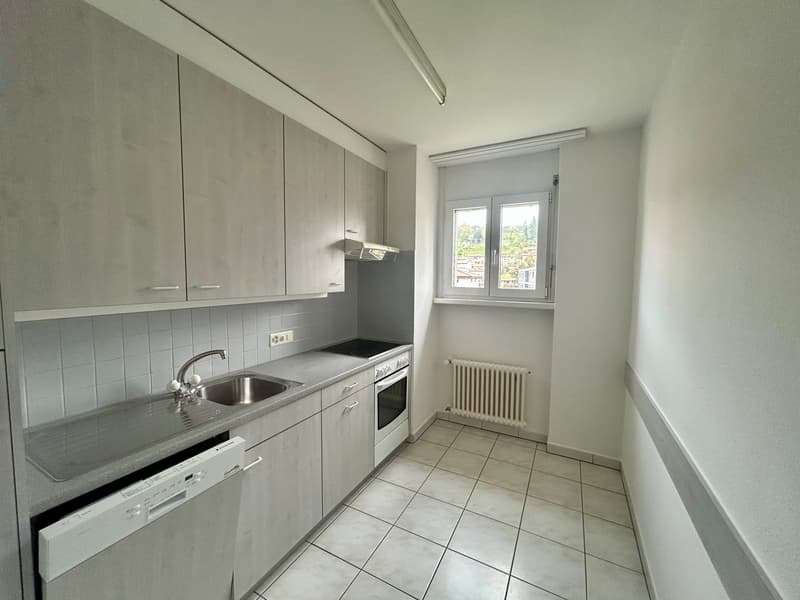 Spacious kitchen with grey cabinets, tiled floor, stainless steel sink, and a dishwasher