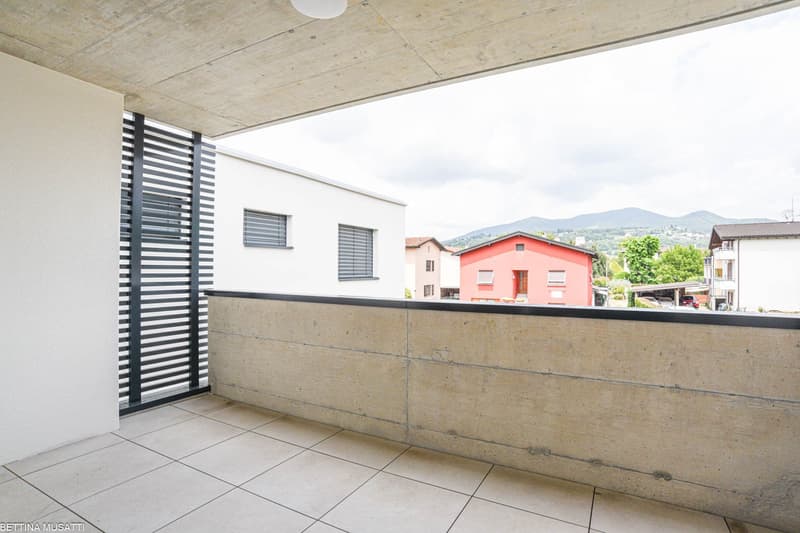 Modern balcony with white tiles, concrete parapet, metal railing