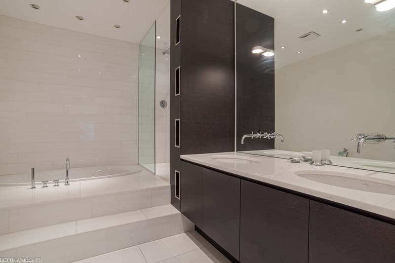 white tiles, large mirror, double sink, bathtub with shower
