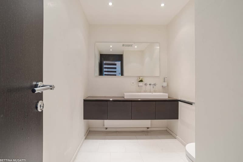 modern minimalist bathroom with white tile flooring, vanity with a sink and mirror, wooden door