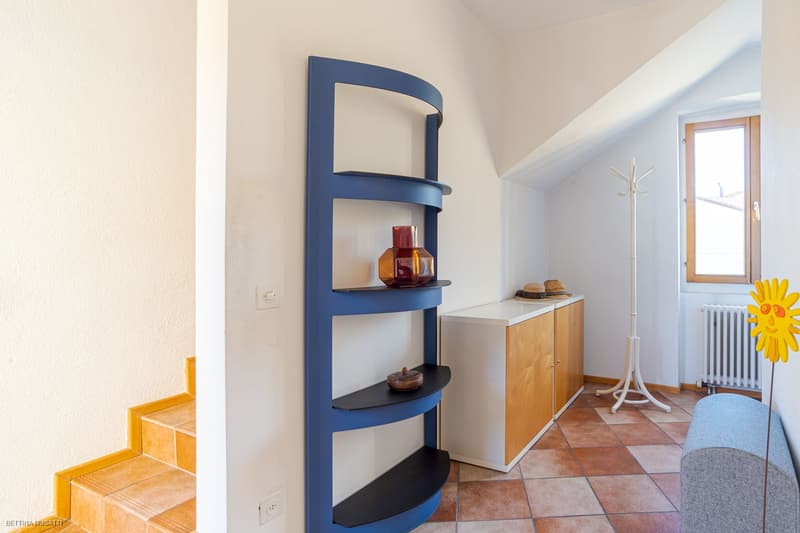 modern room with wooden floor, white and yellow walls, modern shelf, wooden cabinet, radiator, window, stairs