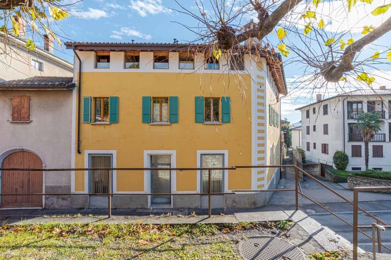 yellow exterior with brown accents, 3 stories, green shutters, 2 windows on each floor, metal railings