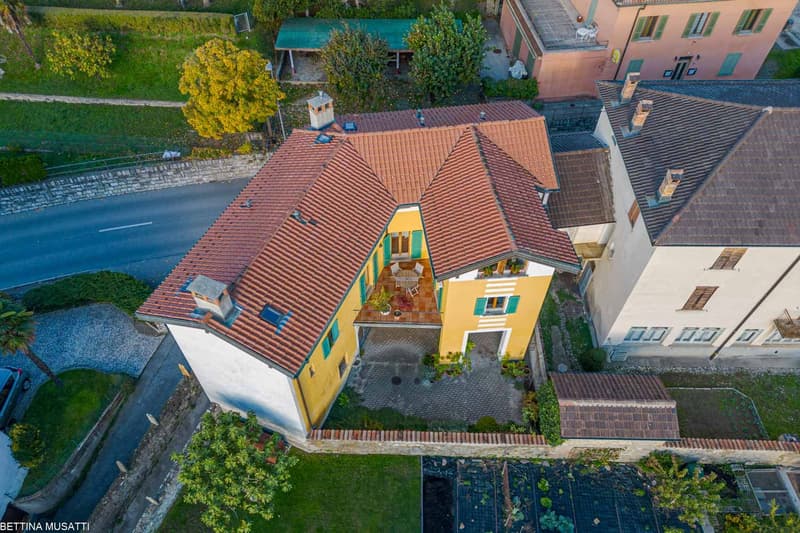 2 story house, yellow exterior, brown roof, balcony, central courtyard, surrounded by trees