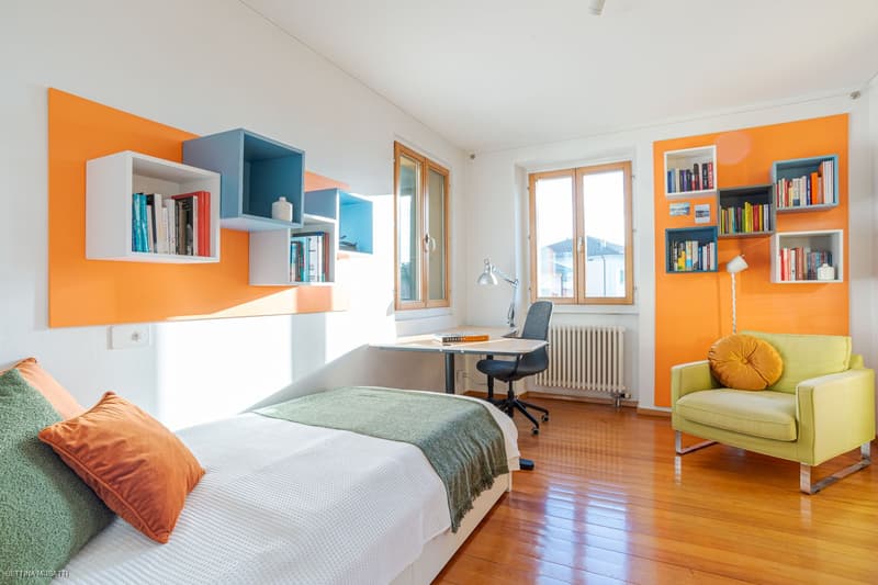 single bed, wooden floor, wall shelves, desk, chair, armchair, radiator, lamps