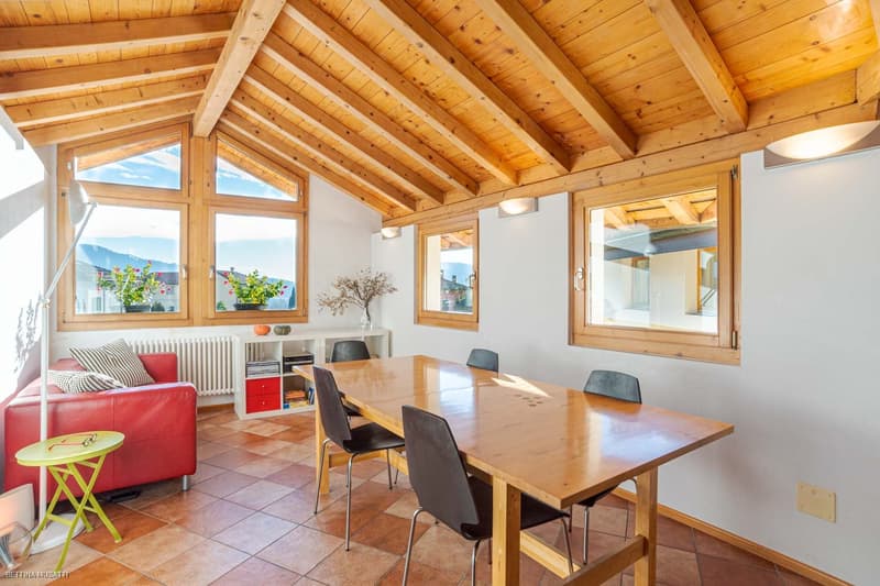 wooden ceiling, large windows, red couch, dining table, bookshelves, side table