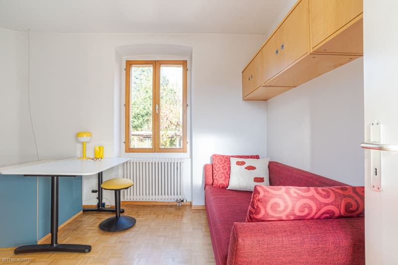 modern room, white walls, wooden flooring, window, radiator, red sofa, table, stool, lamp