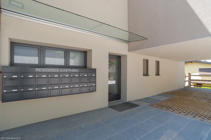 External entrance to residential building with mailboxes and a paved courtyard area