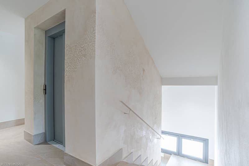 Decorated wall, tiled floor, elevator, staircase, windows
