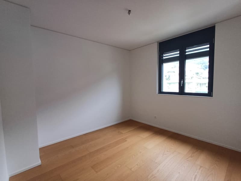 Empty room, white walls, hardwood floor, large window, power outlet