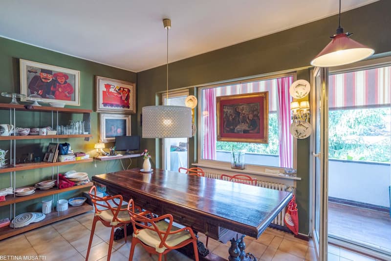 dining table, chairs, wooden shelves, paintings on the wall, floor lamp, radiator, glass doors to balcony