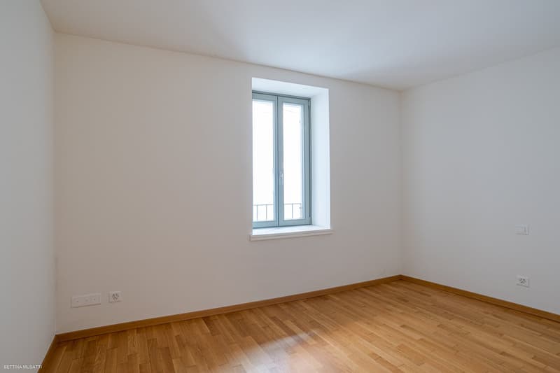 empty room, white walls, wooden floor, window with balcony, power outlets